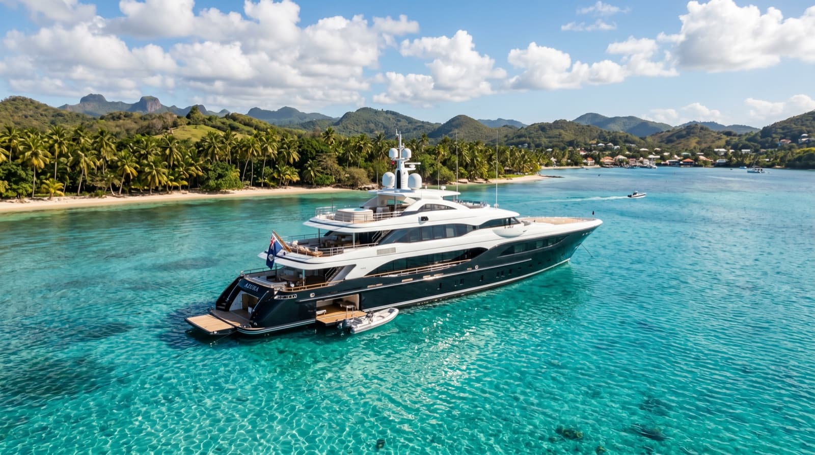 A dark hulled superyacht anchored in calm turquoise water off a palm fringed shore